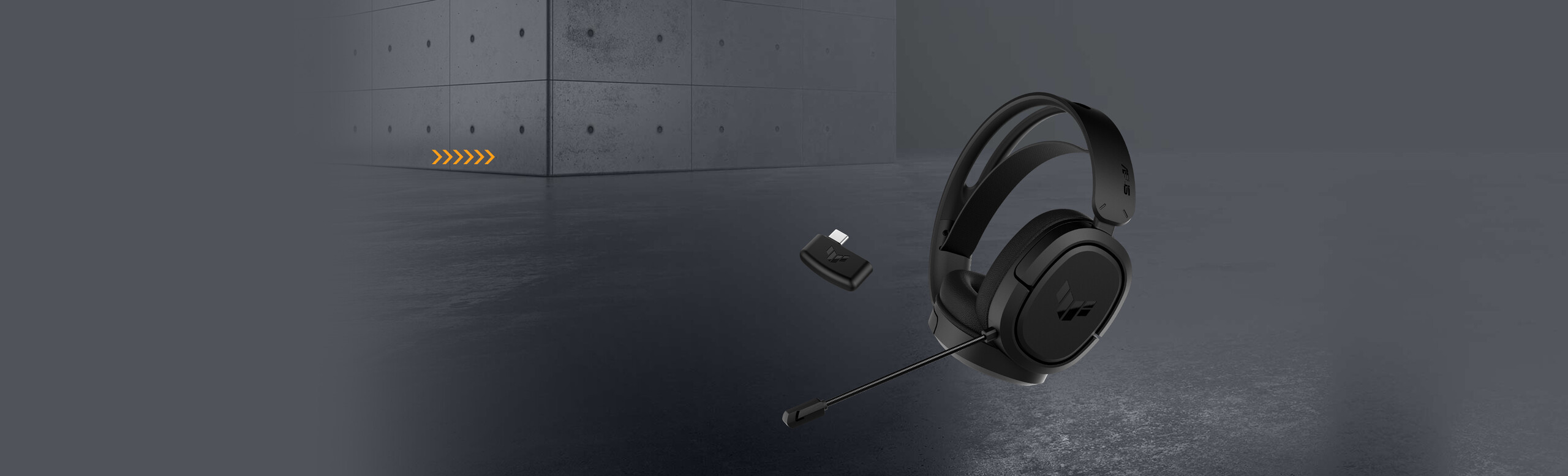 L'immagine mostra un paio di cuffie da gaming TUF Gaming H1 Wireless con dongle wireless su fondo grigio