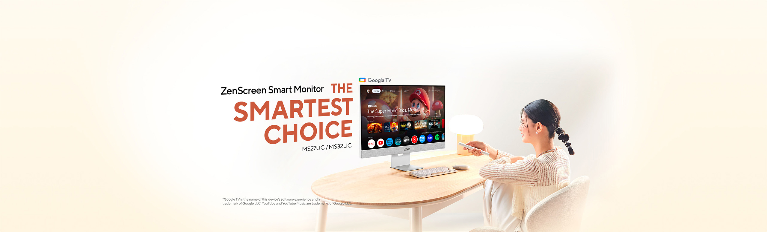 Lifestyle scene showing a woman at a light‑wood table using a remote to control an ASUS ZenScreen Smart Monitor (MS27UC / MS32UC) displaying the Google TV interface under the headline “ZenScreen Smart Monitor – THE SMARTEST CHOICE” on a soft beige background