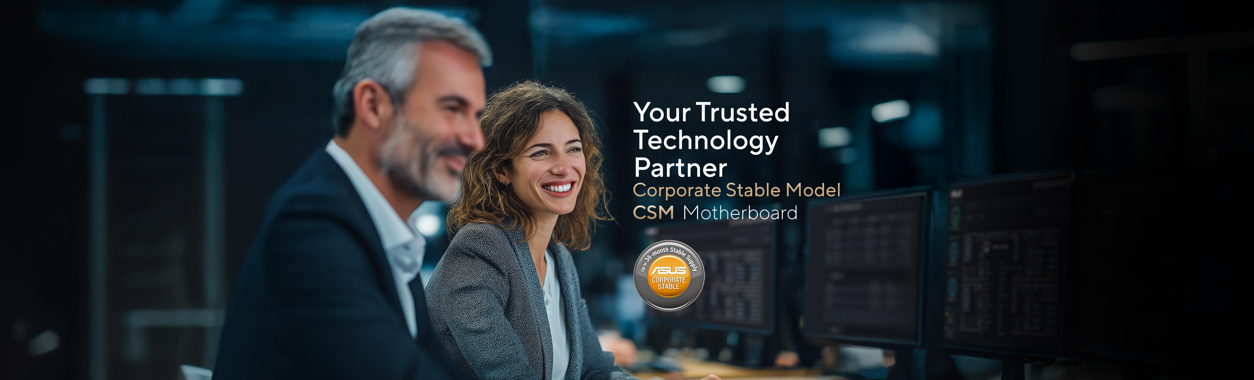 A man in a suit and a woman with wavy, light brown hair wearing a business jacket and white shirt are seated together at a desk in a modern office setting. Computer monitors are visible in the background, alongside promotional text for ASUS Corporate Stable Model (CSM) Motherboard: Your Trusted Technology Partner Program, and a circular badge stating 'Up to 36-month Stable Supply.'