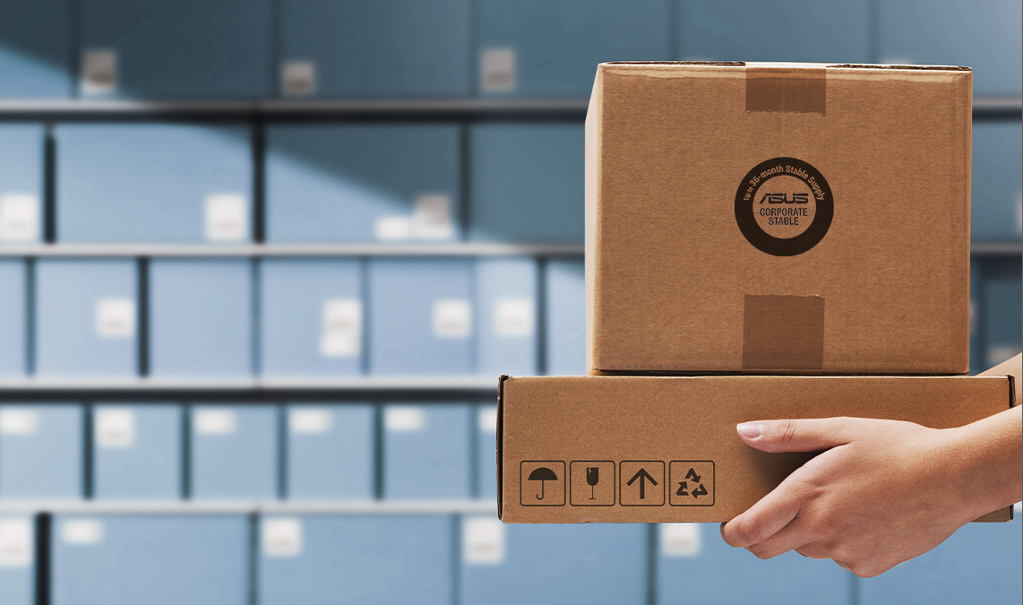 A hand holding two cardboard boxes with packaging symbols, in front of shelves filled with many other cardboard boxes, illustrating a variety of packaging options for CSM motherboards.